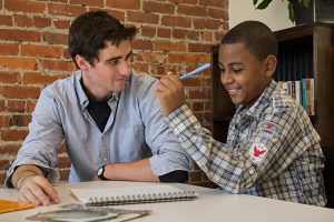 Fordham senior Harrison Pidgeon (left), a volunteer with POTS's Family Club program, helps Rayvon learn long division. (Photo by Bud Glick) 
