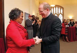 Joseph M. McShane, S.J., president of Fordham, congratulates Georgia Edwards of Custodial Services, who “shows up for work every day, early, ready and proud.”  Photo by Bruce Gilbert