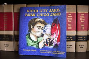 A copy of Mark Torres' children's book, Good Guy Jake aka Buen Chico Jake, stands out on a shelf of legal books in his Long Island City office.