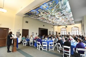 Marymount alumnae sit around tables in Butler Commons, under the reproduction of Michaelangelo's Sistine Chapel paining.