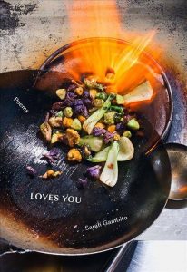 Front cover of "Loves You." Features a pan filled with food and flames.