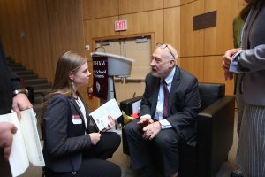 Joseph Stiglitz speaks with a young woman on stage after the conversation. 