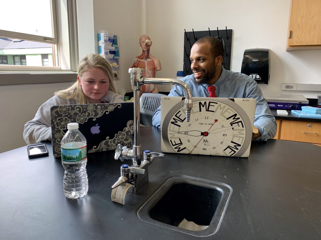 A student and professor sitting together in the lab room.