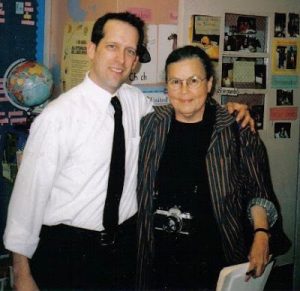 A man and a woman smile at the camera in a classroom.