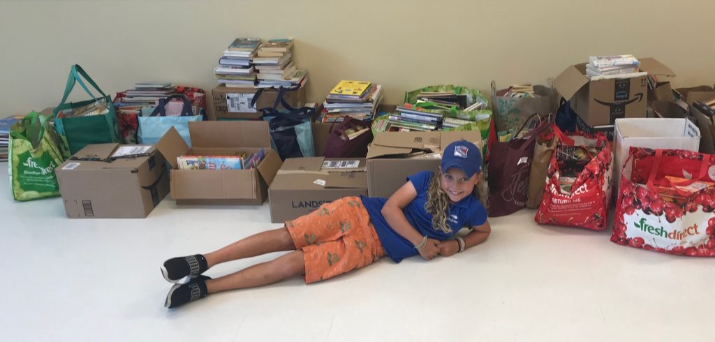 A girl laying in front of cardboard boxes filled with books