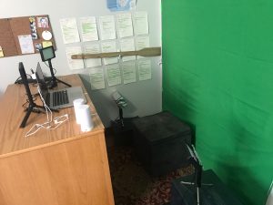 a desk with a green screen behind it.