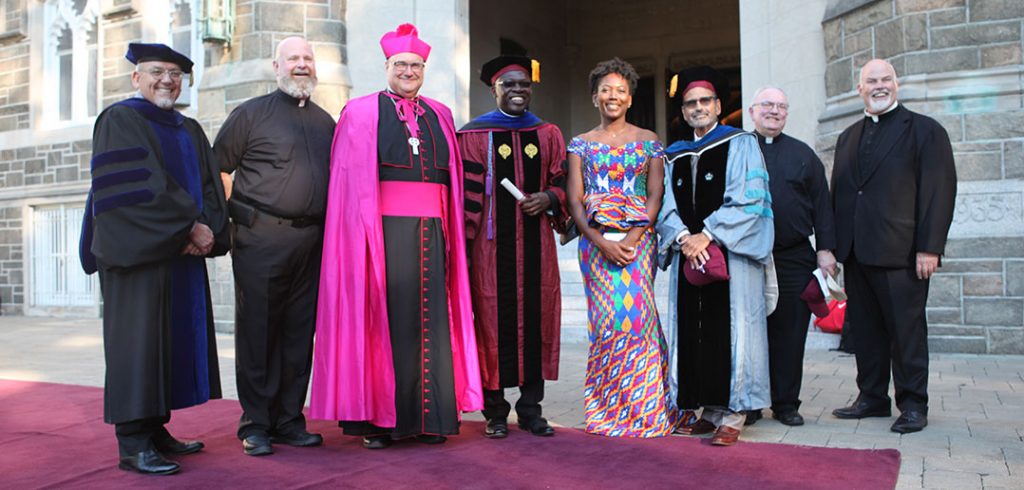 Monsignor Richard G. Henning, Auxiliary Bishop of Diocese of Rockville Centre, standing with a group, including two doctoral students, Collins Adutwum, Ph.D., and Valerie Serpe, Ph.D.