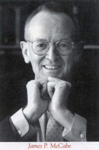 A black and white portrait of a man wearing glasses and propping his chin up with his hands