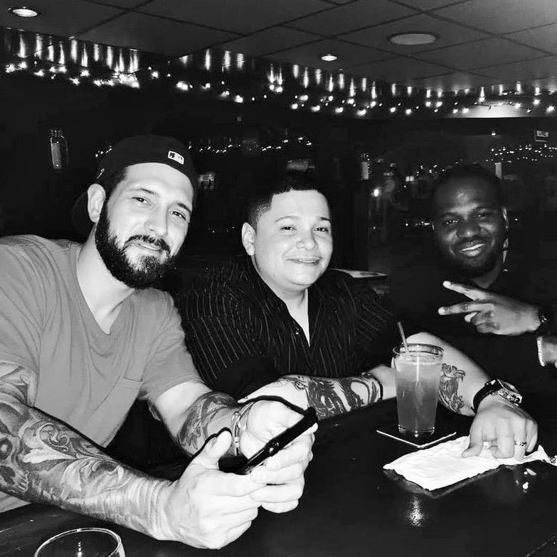 Three men smile in a black and white photo.