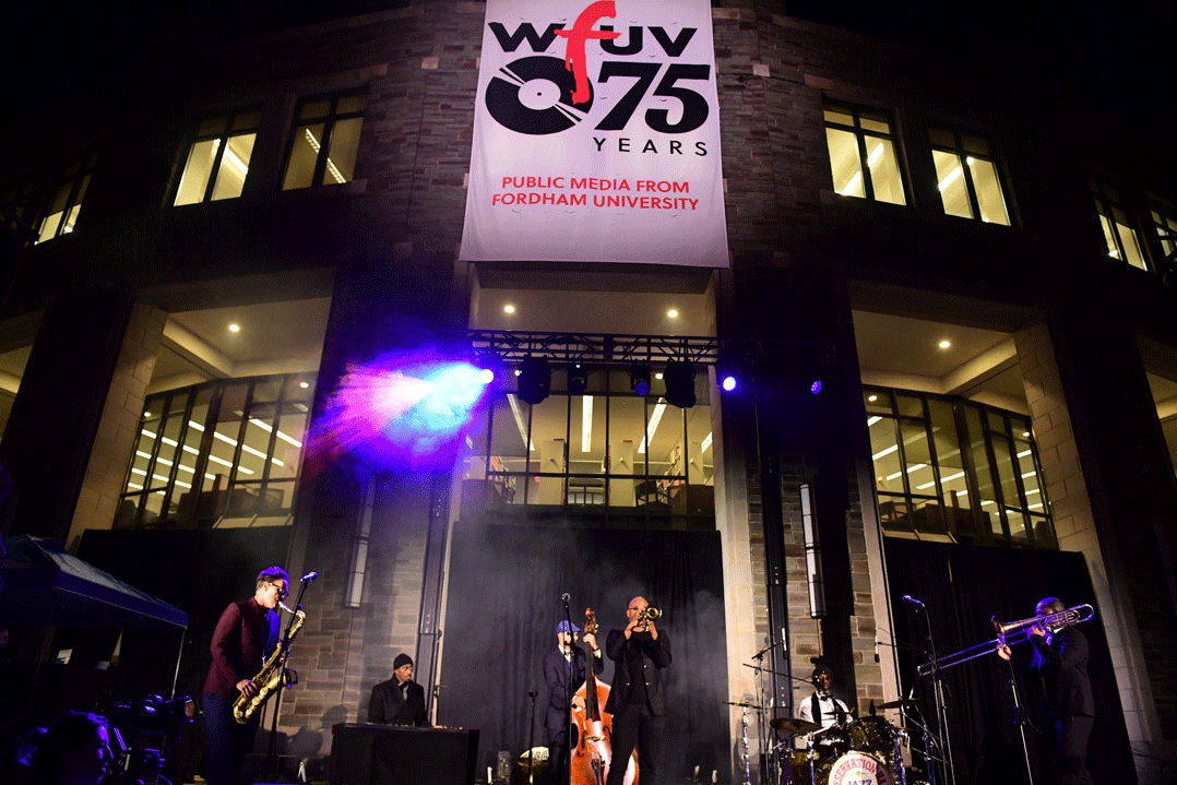 Band under a WFUV banner outside at night