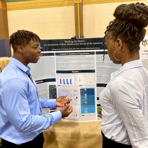 Latif Diaoune shows his research poster to a young woman.