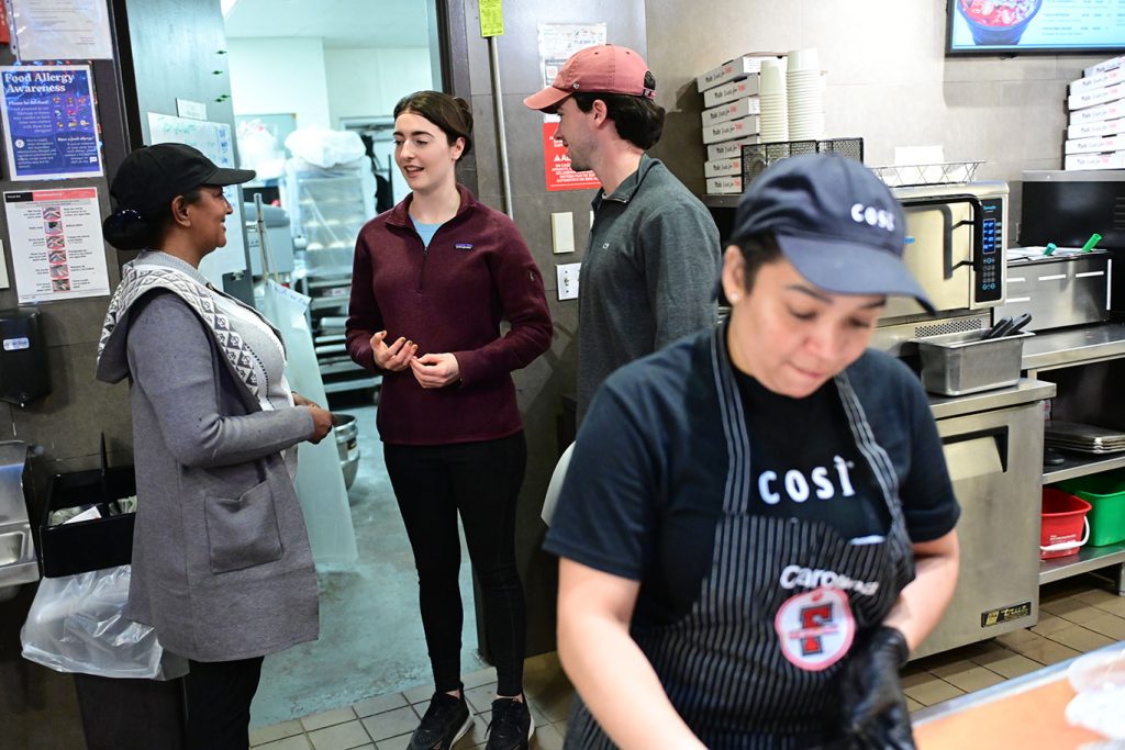 Two students speak to a worker outside a kitchen